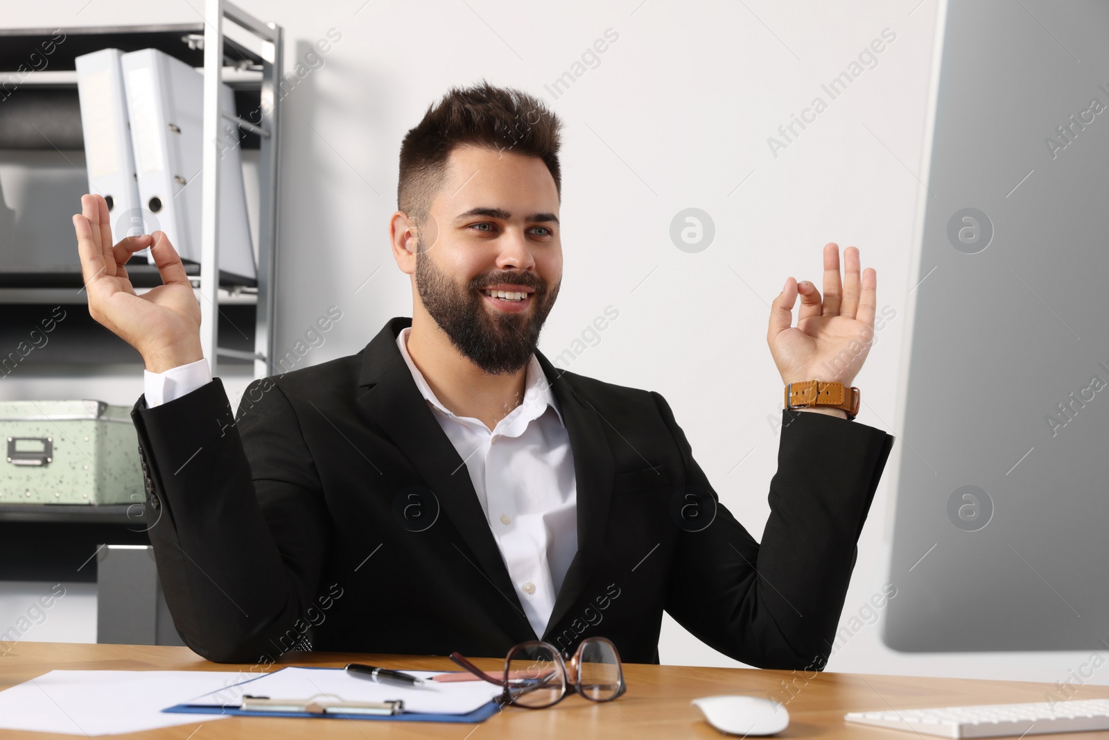 Photo of Young businessman meditating at workplace. Zen concept