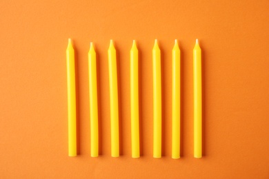 Photo of Yellow birthday candles on orange background, top view