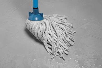 Photo of Cleaning grey floor with string mop, closeup