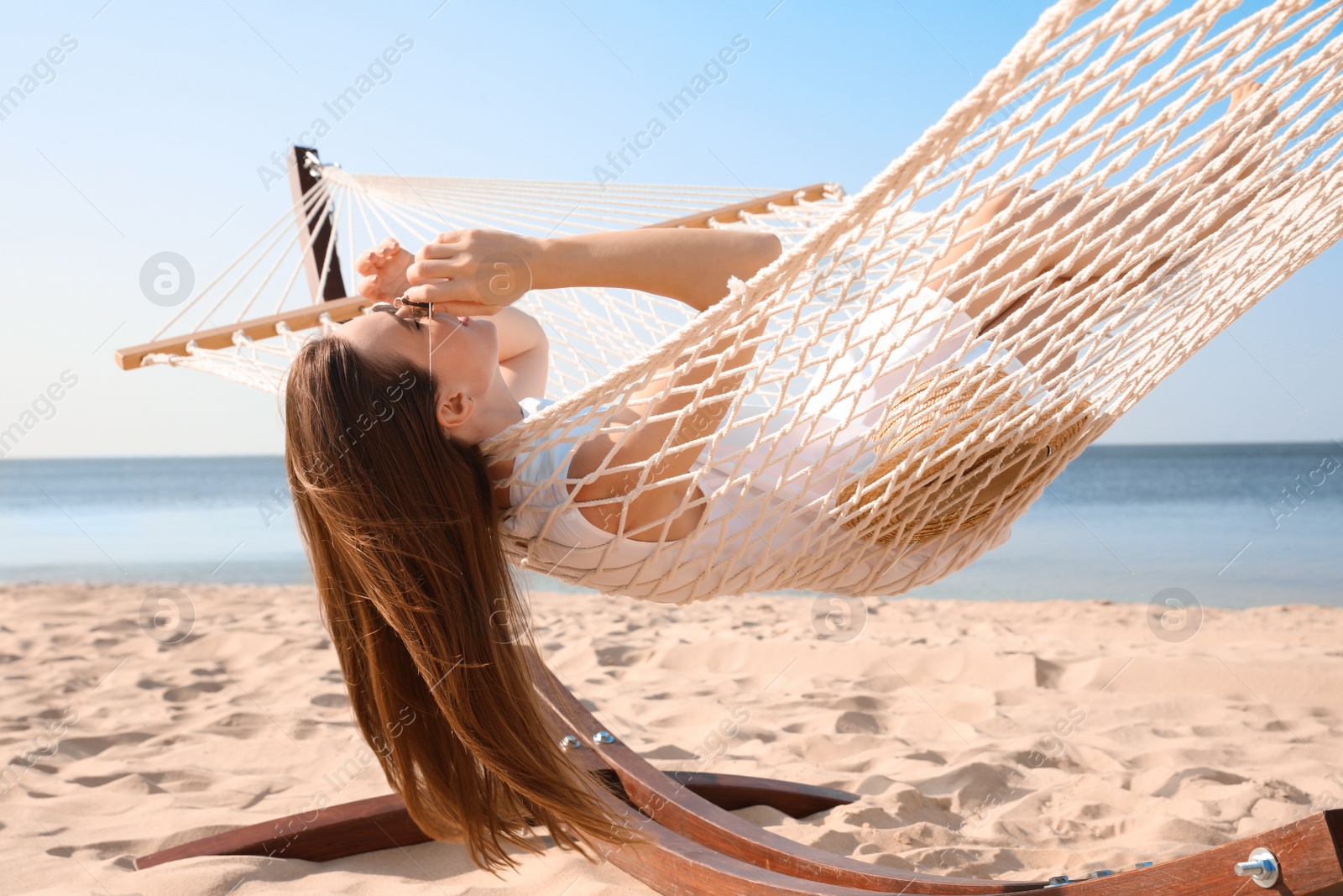 Photo of Young woman relaxing in hammock on beach