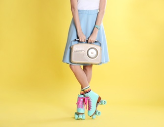Photo of Young woman with roller skates and retro radio on color background, closeup