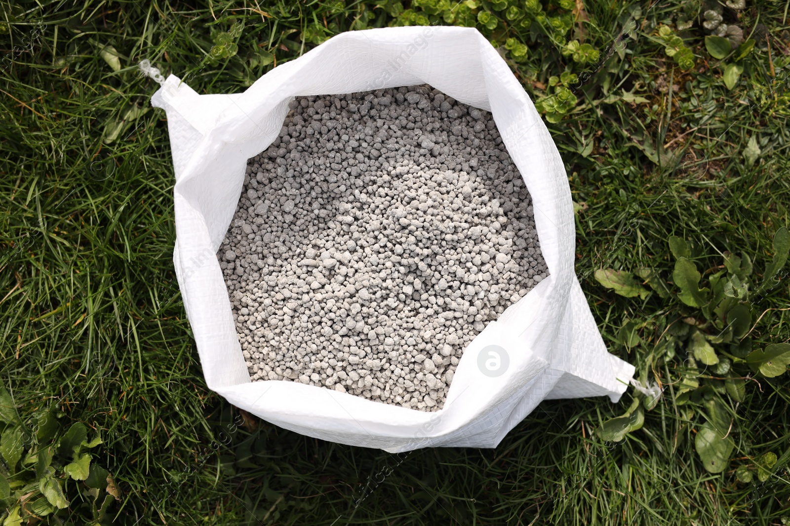 Photo of Fertilizer in bag on green grass outdoors, top view