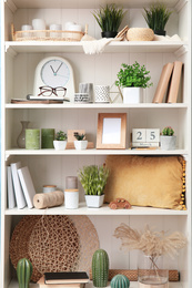 Photo of White shelving unit with plants and different decorative stuff