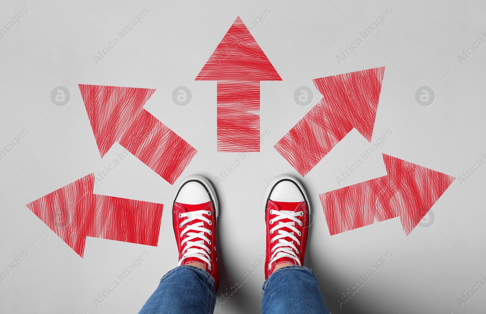 Image of Choosing future profession. Girl standing in front of drawn signs on grey background, top view. Arrows pointing in different directions symbolizing diversity of opportunities