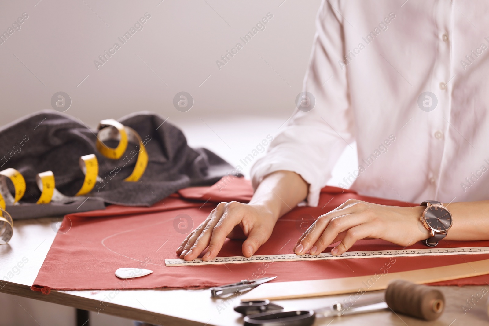 Photo of Tailor working with cloth at table in atelier