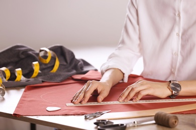 Tailor working with cloth at table in atelier