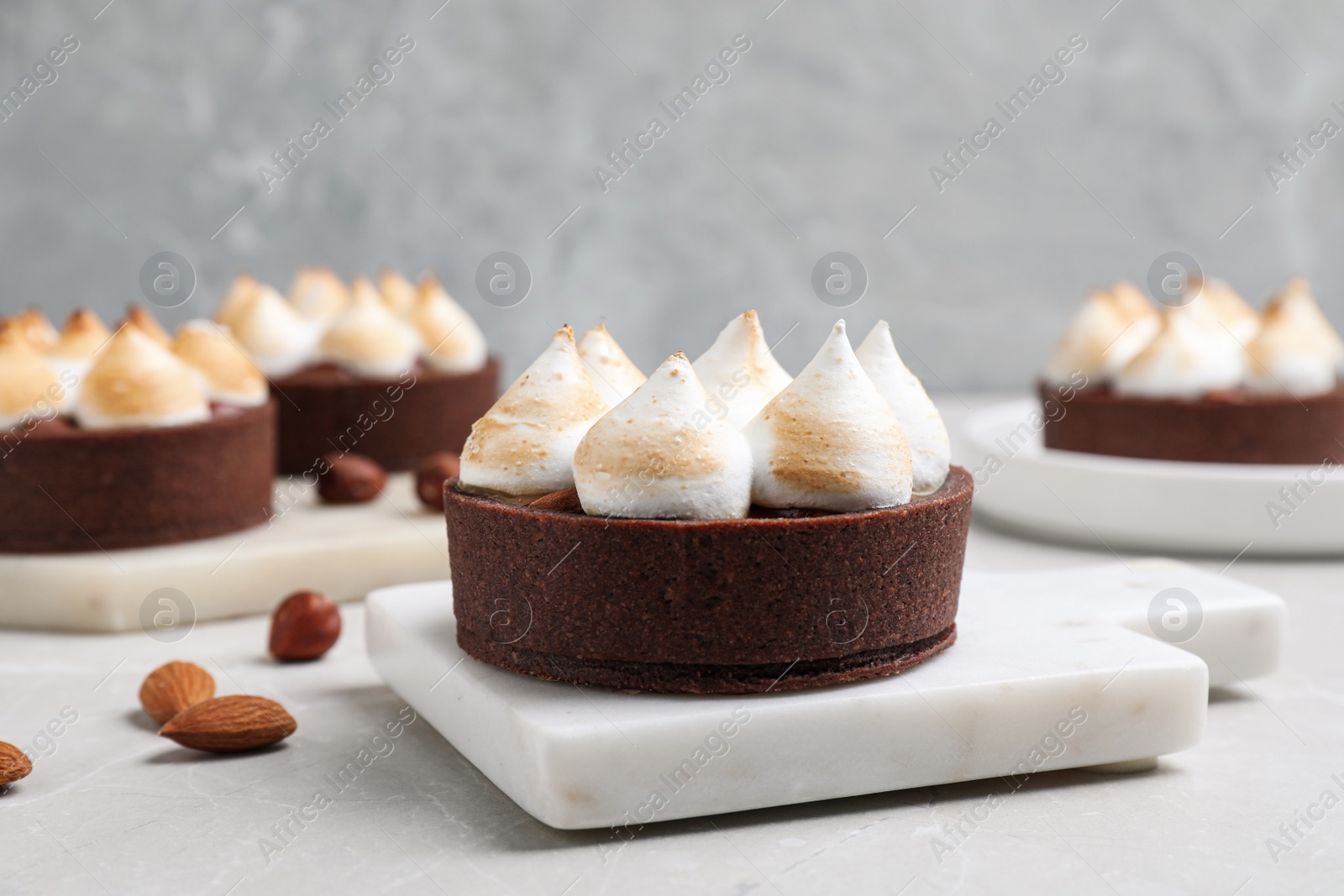 Photo of Delicious salted caramel chocolate tart with meringue on light grey table
