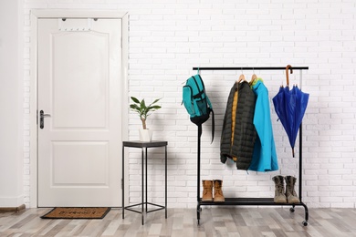 Photo of Stylish hallway interior with shoes and clothes on hanger stand