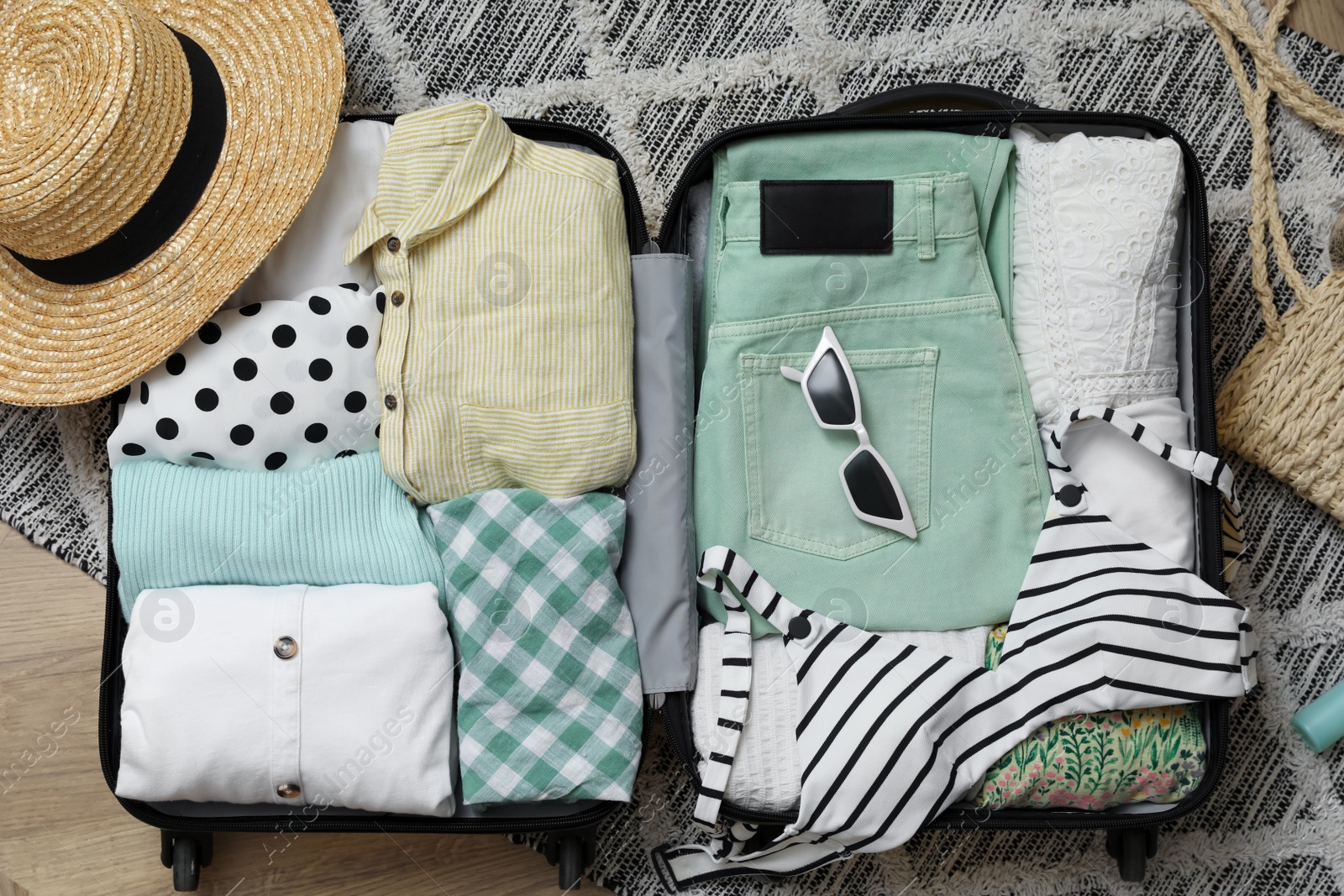 Photo of Open suitcase with summer clothes and accessories on floor, flat lay