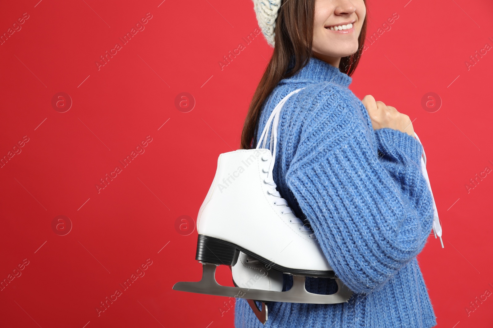 Photo of Happy woman with ice skates on red background, closeup. Space for text