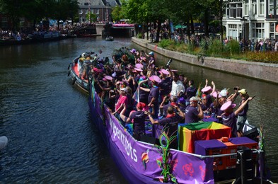 Photo of AMSTERDAM, NETHERLANDS - AUGUST 06, 2022: Many people in boats at LGBT pride parade on river