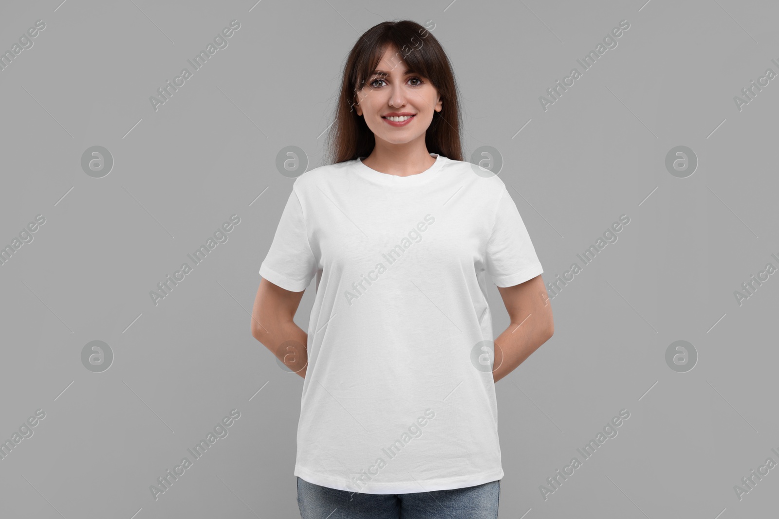 Photo of Smiling woman in white t-shirt on grey background