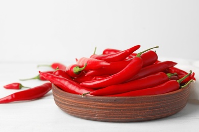 Photo of Wooden bowl with red hot chili peppers on white table