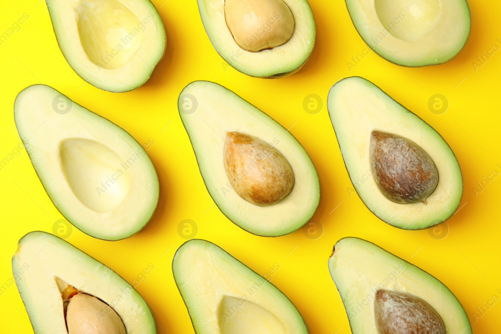 Photo of Cut fresh ripe avocados on yellow background, flat lay