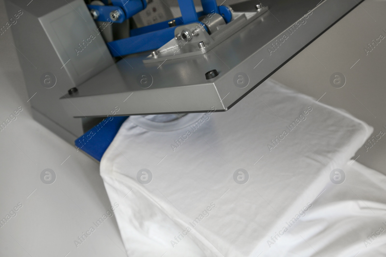 Photo of Printing logo. Heat press with t-shirt on white table