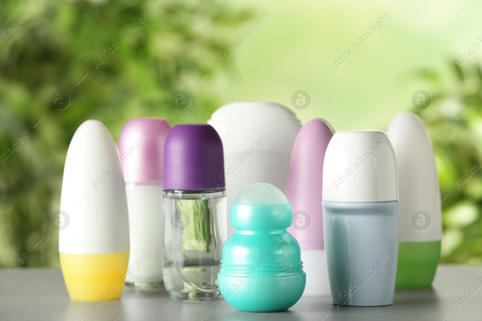 Photo of Different deodorants on white wooden table against blurred background