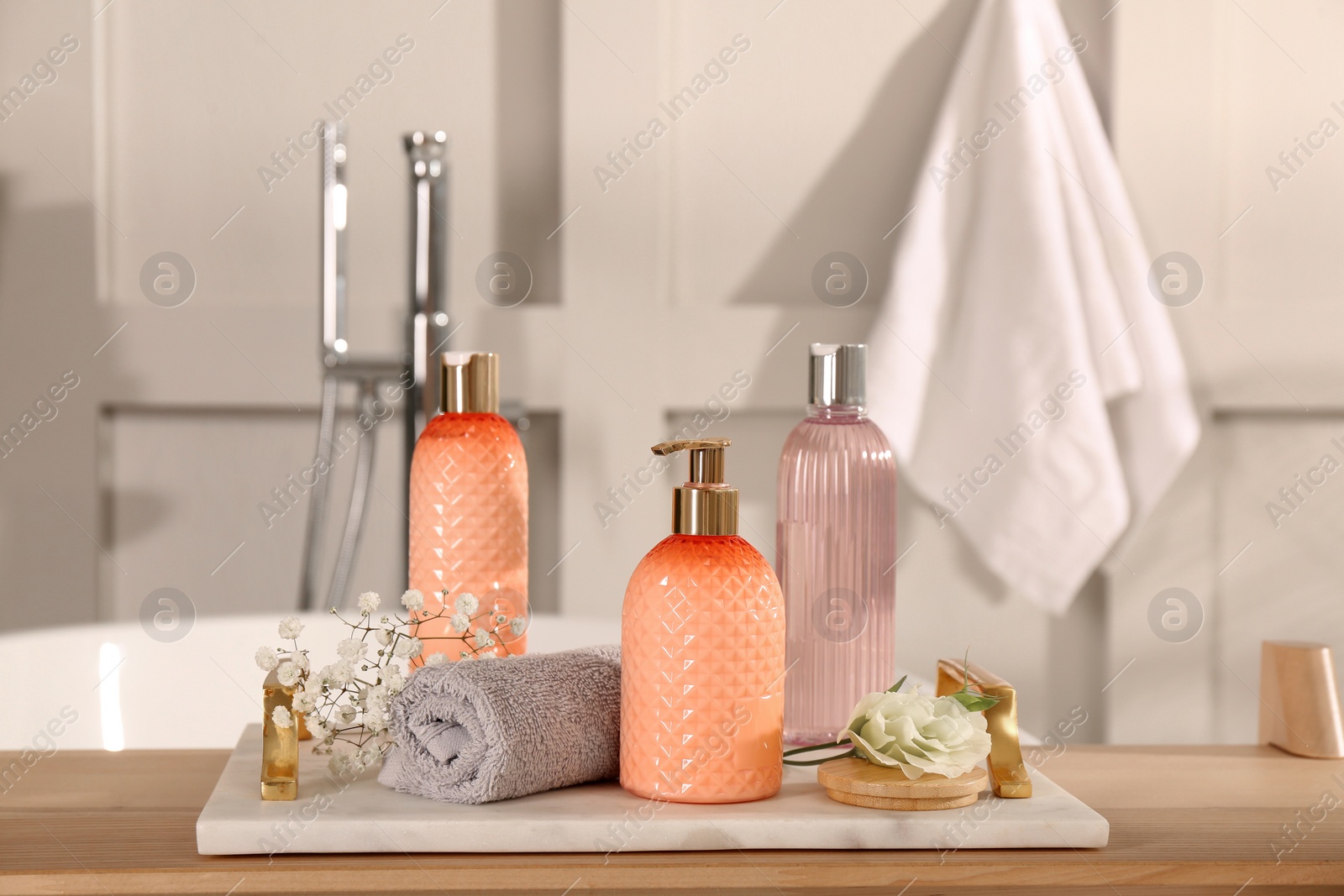 Photo of Liquid soap and other toiletries on wooden table in bathroom