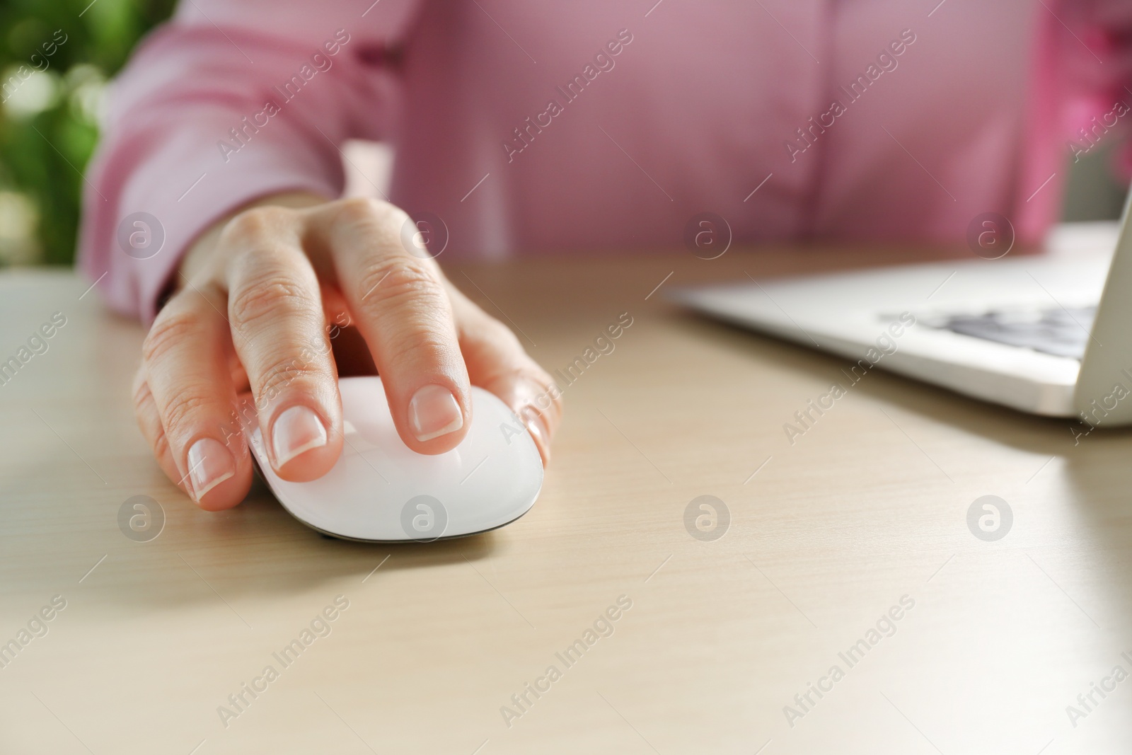 Photo of Woman using computer mouse with laptop at table, closeup