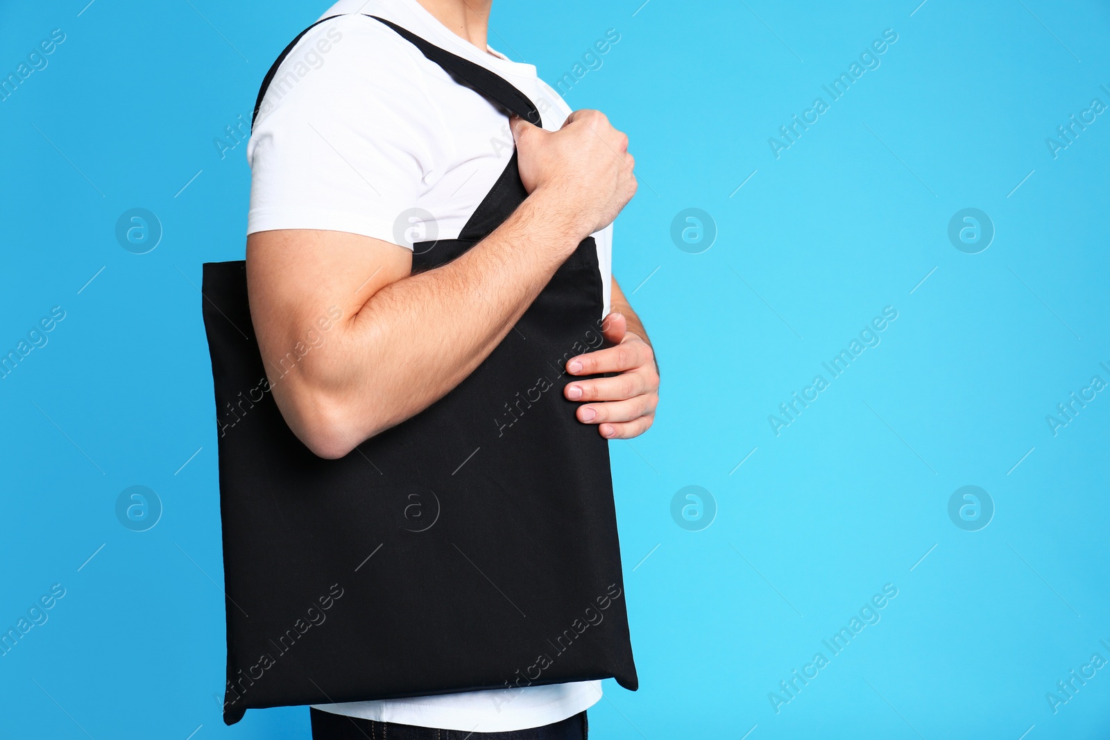 Photo of Young man with eco bag on blue background, closeup. Space for text