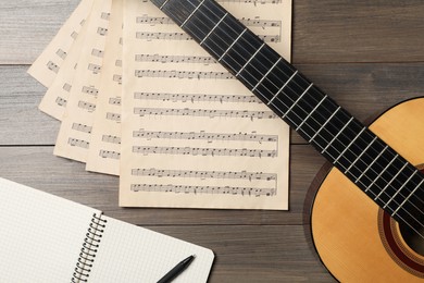 Photo of Composition with guitar and music notations on wooden table, flat lay
