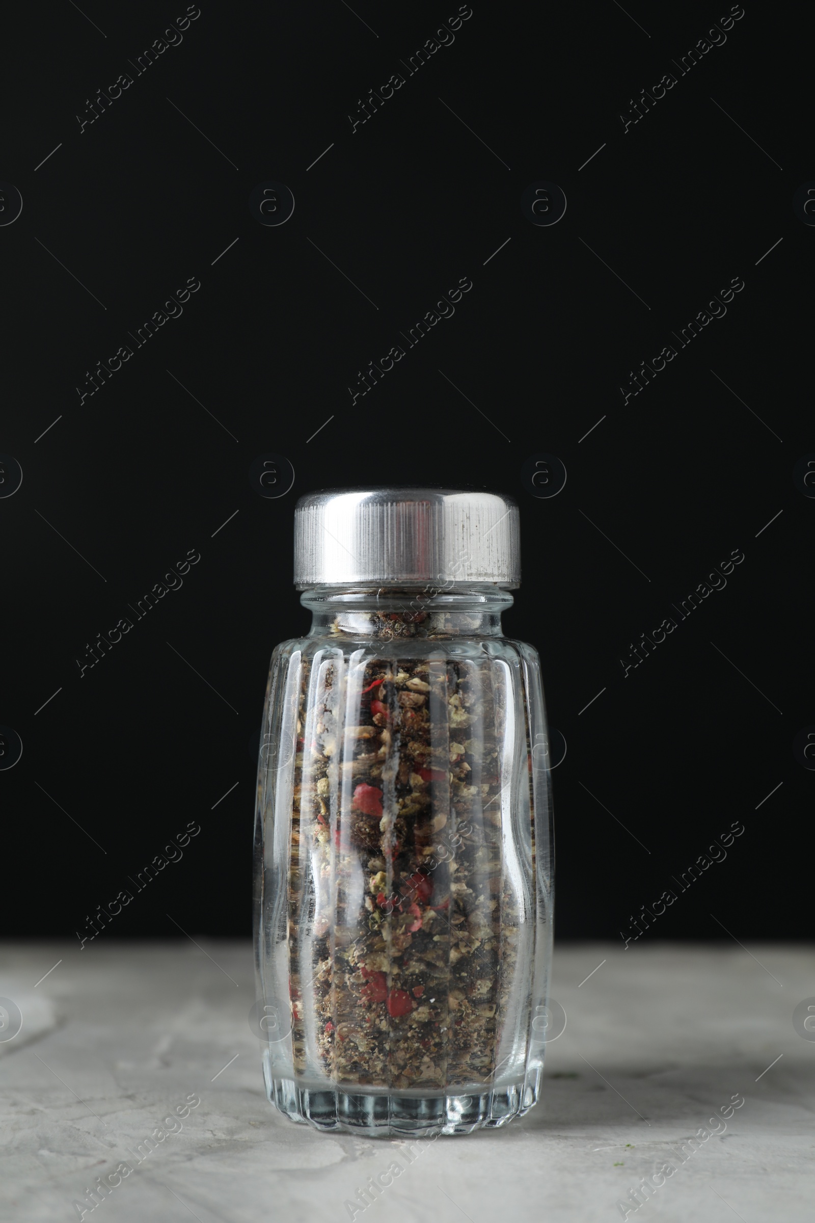 Photo of Pepper shaker on light textured table against black background