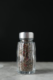 Pepper shaker on light textured table against black background