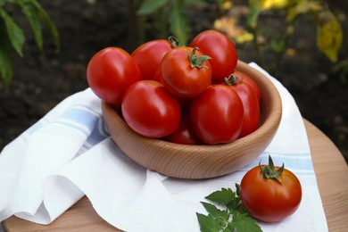 Photo of Bowl and fresh tomatoes on wooden table outdoors