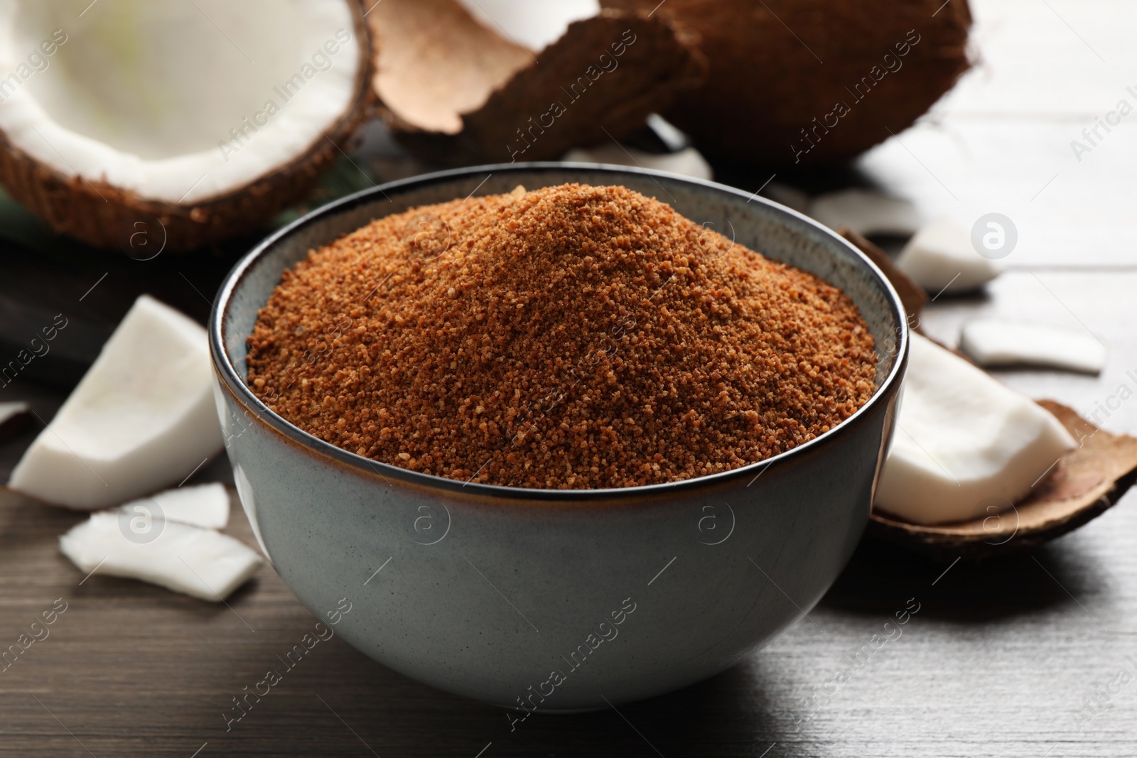 Photo of Natural coconut sugar in ceramic bowl on wooden table