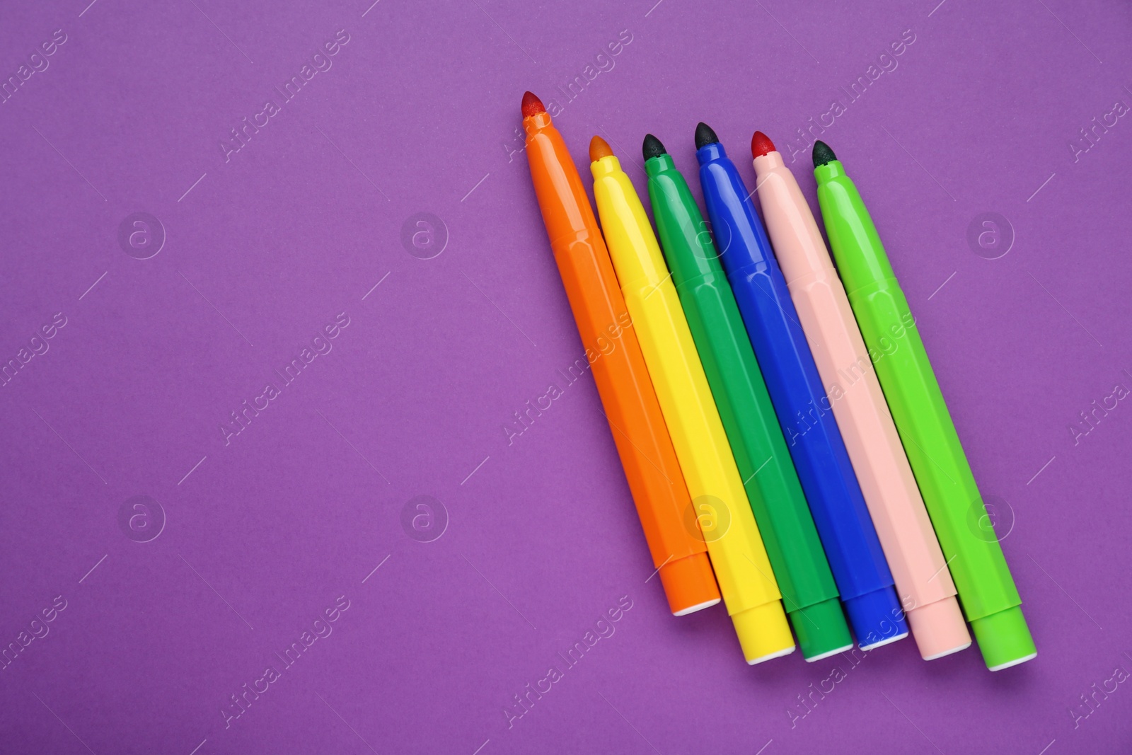 Photo of Different colorful markers on purple background, flat lay. Space for text