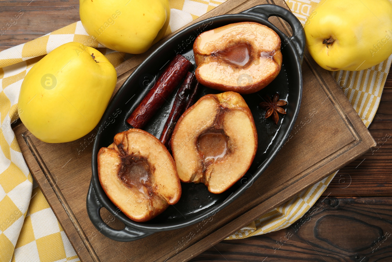 Photo of Tasty baked quinces with spices and honey in dish on wooden table, flat lay