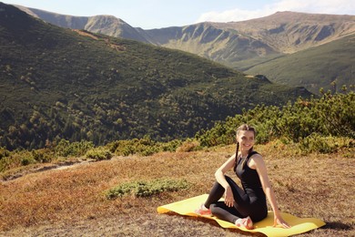 Photo of Beautiful young woman practicing yoga in mountains on summer morning