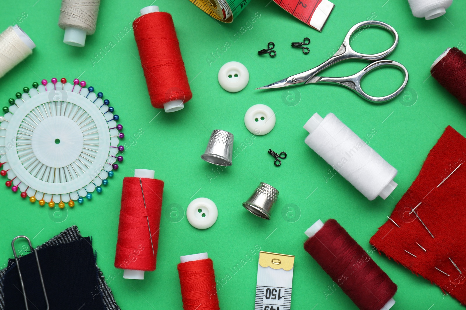 Photo of Flat lay composition with thimbles and different sewing tools on green background