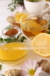 Cup of delicious tea, honey and lemon on white wooden table