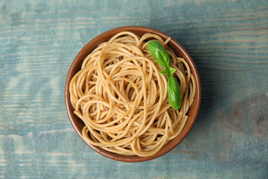 Photo of Tasty buckwheat noodles in bowl on blue wooden table, top view