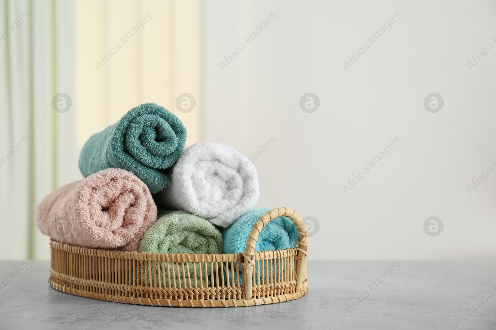 Photo of Rolled color towels on light grey stone table in bathroom. Space for text