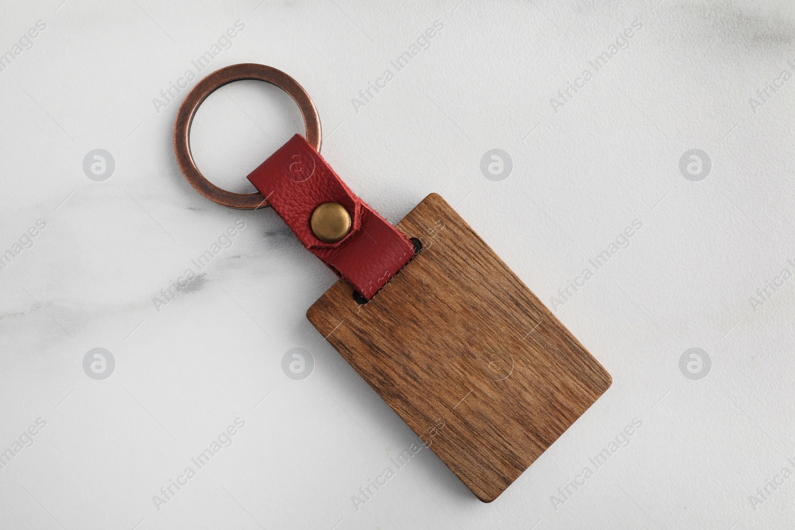 Photo of Wooden keychain with Ukrainian coat of arms on white marble table, top view