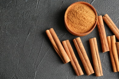 Photo of Aromatic cinnamon sticks and powder on dark grey background