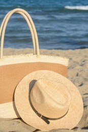 Photo of Stylish bag and hat near sea on sunny day. Beach accessories