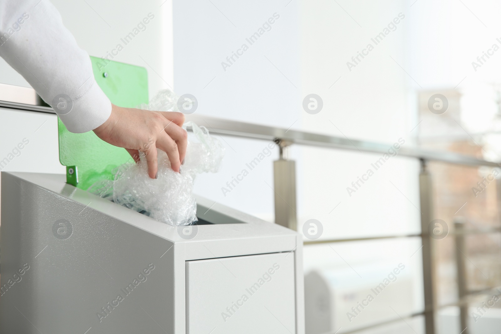 Photo of Young woman throwing plastic film in metal bin indoors, closeup with space for text. Waste recycling