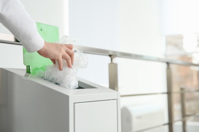 Young woman throwing plastic film in metal bin indoors, closeup with space for text. Waste recycling