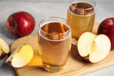 Photo of Delicious cider and ripe red apples on grey table