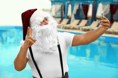 Authentic Santa Claus taking selfie near pool at resort