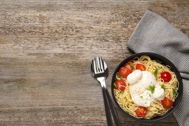 Delicious spaghetti with burrata cheese and tomatoes on wooden table, flat lay. Space for text