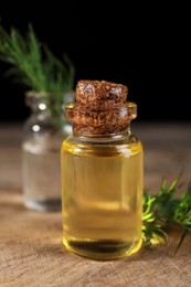 Bottles of essential oil and fresh dill on wooden table, closeup