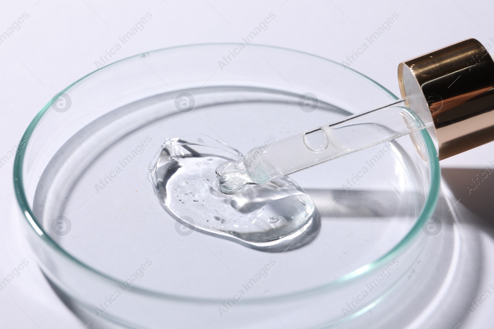 Photo of Petri dish with sample of cosmetic serum and pipette on white background, closeup