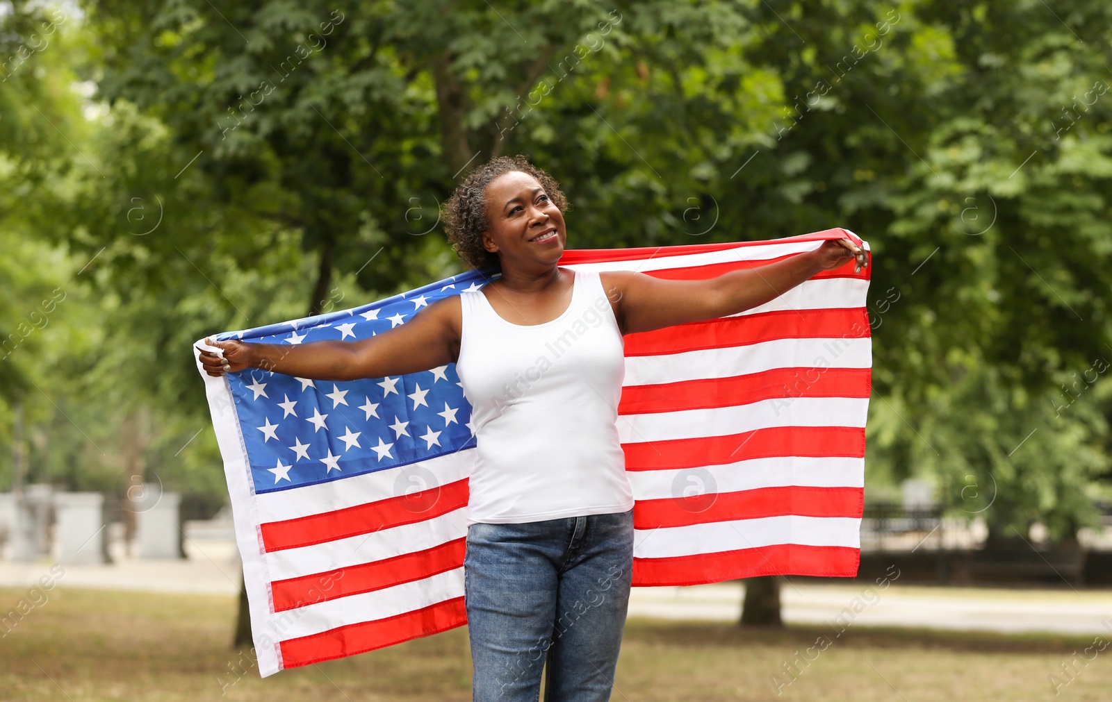 Photo of Portrait of happy African-American woman with USA flag in park