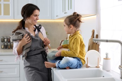 Young mother and her daughter spending time together in kitchen