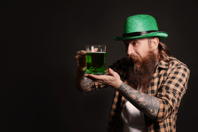 Photo of Bearded man with green beer on black background, space for text. St. Patrick's Day celebration