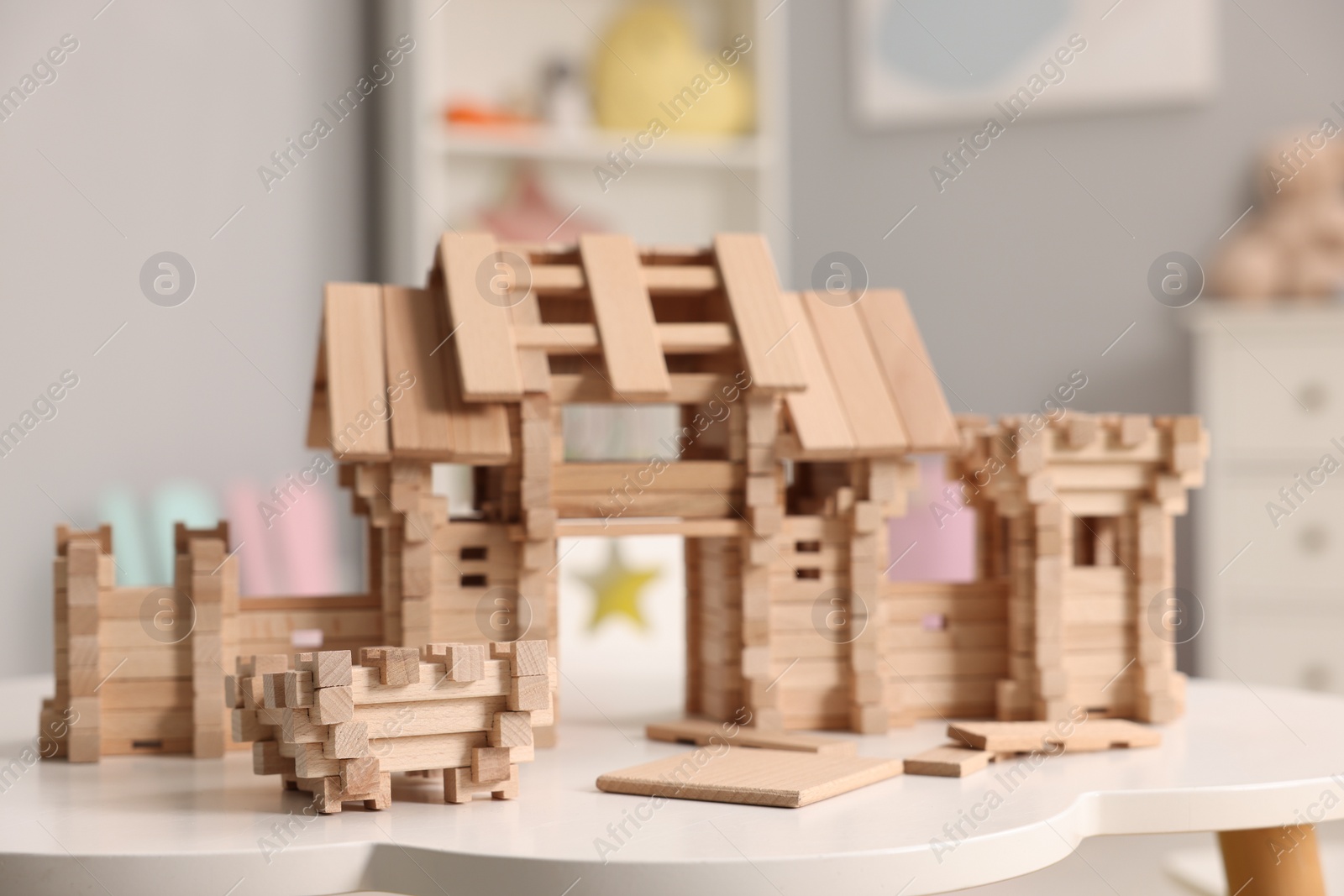 Photo of Wooden entry gate and building blocks on white table indoors. Children's toy