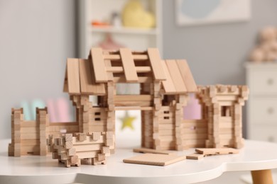 Photo of Wooden entry gate and building blocks on white table indoors. Children's toy